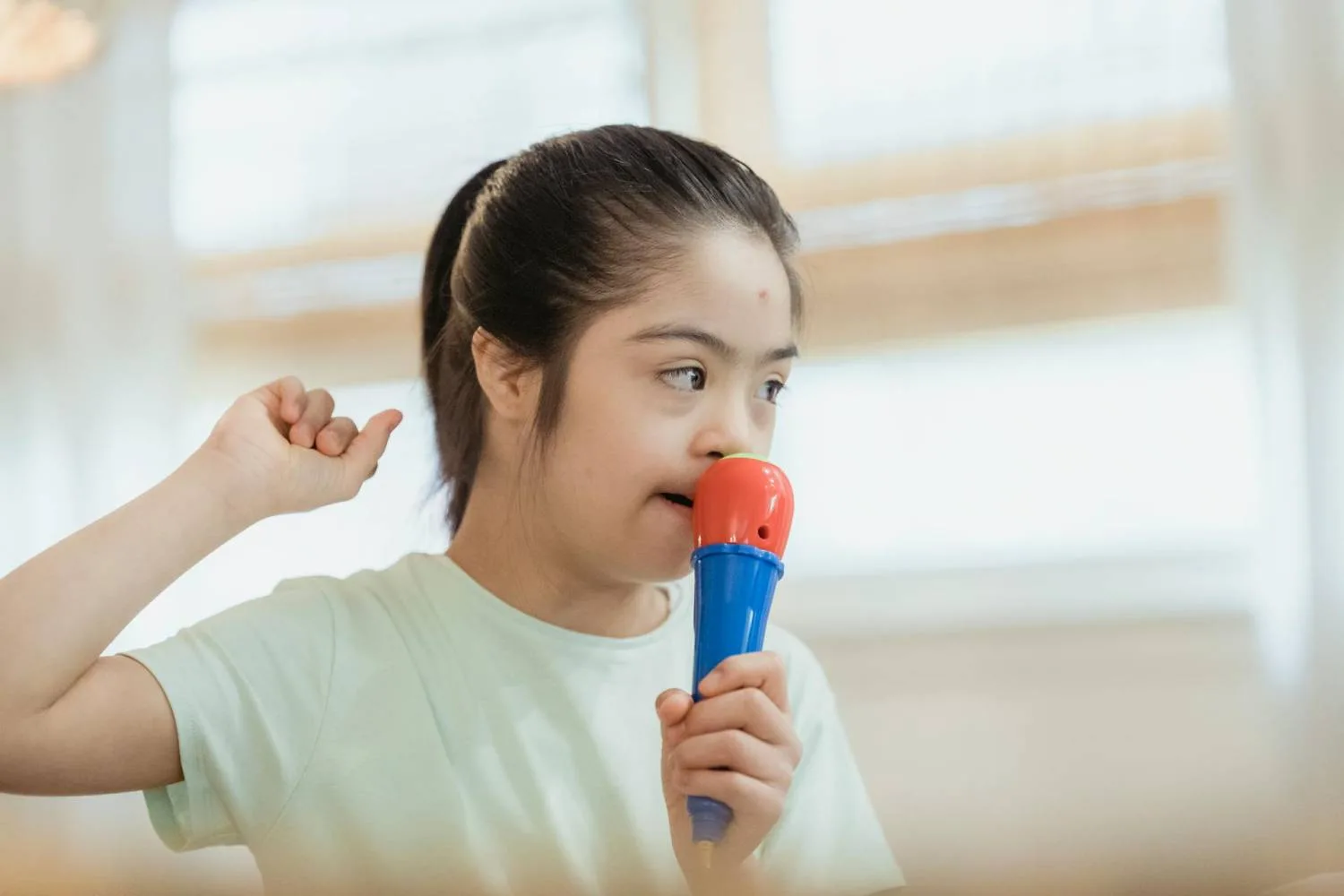 Girl with Down syndrome speaking into a toy microphone