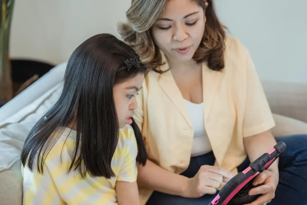 Teacher supporting her student with Down syndrome using a tablet